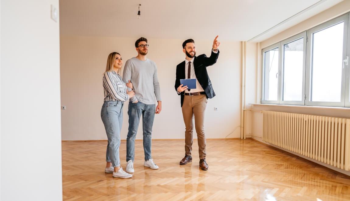 An agent points out features to a couple touring an empty apartment.