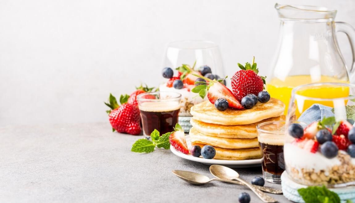 A table filled with pancakes, fruit, and drinks.