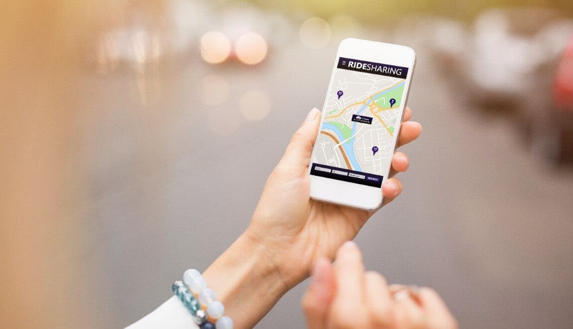 Close-up of a hand holding a phone open to a rideshare app.