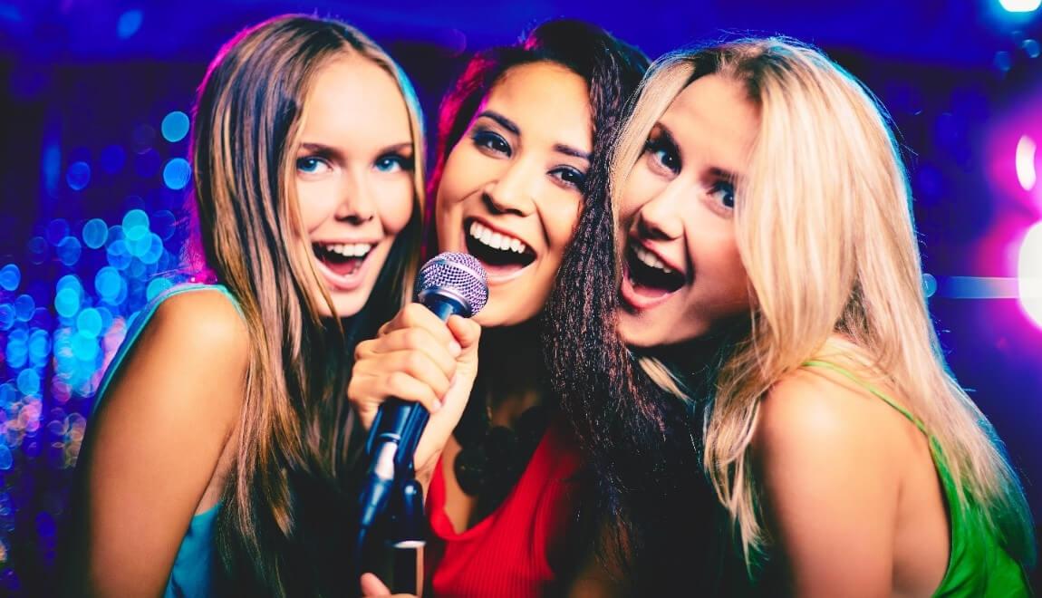 Three women singing into a microphone.