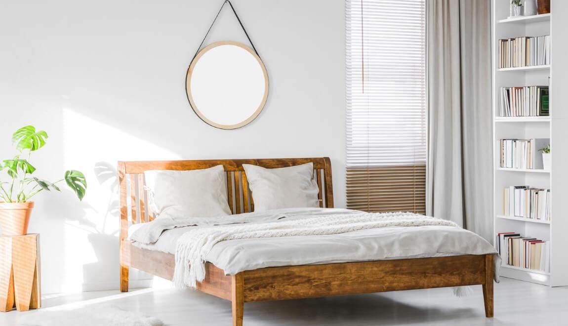 A comfortable white bed with a mirror hanging overhead