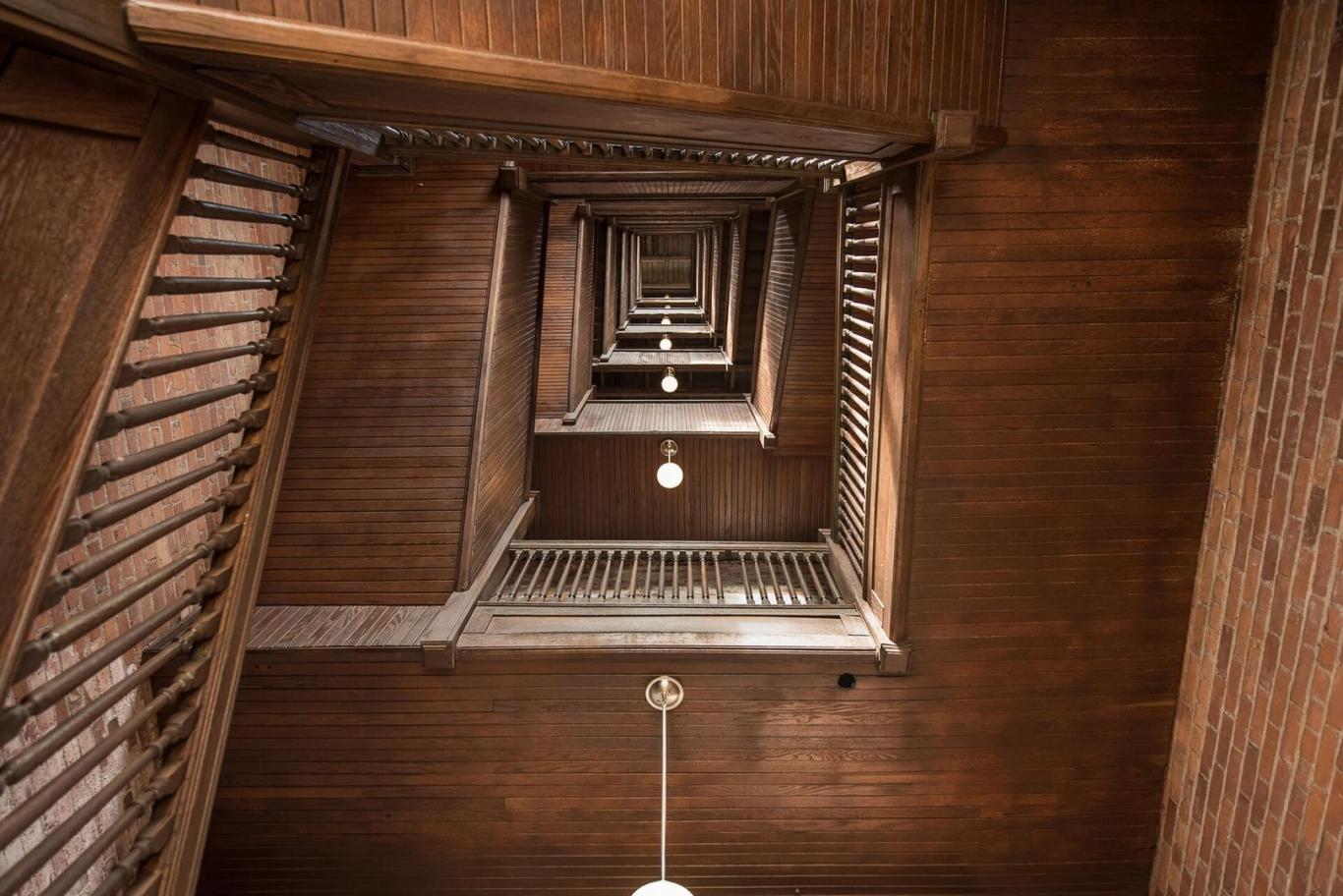 Open stairwell with wood beams and hanging light fixtures.