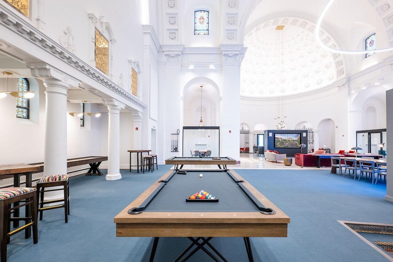 Pool table in a stylish clubhouse with large windows.