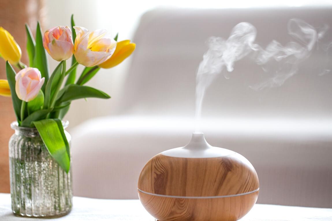 An image of a essential oil diffuser next to a vase of tulips. 