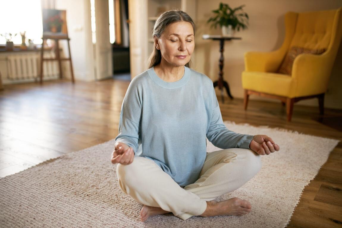 An image of a person meditating in their apartment. 