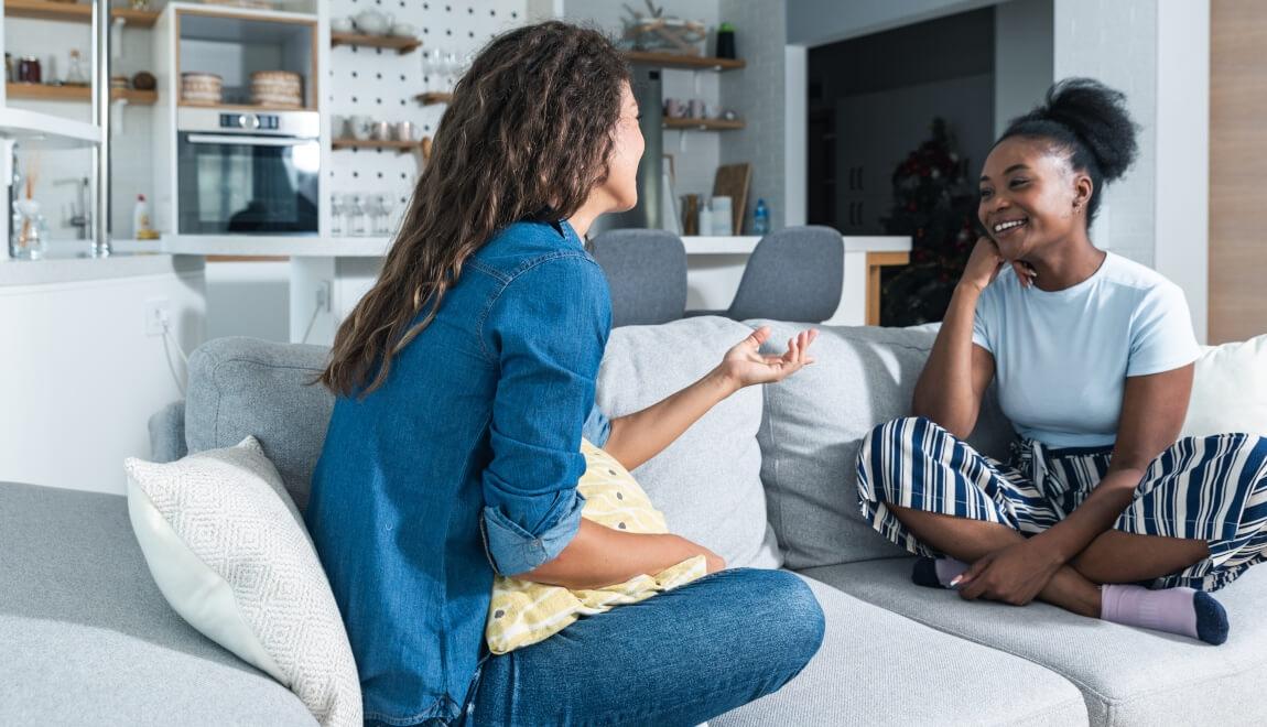 Two young women talking on a couch.