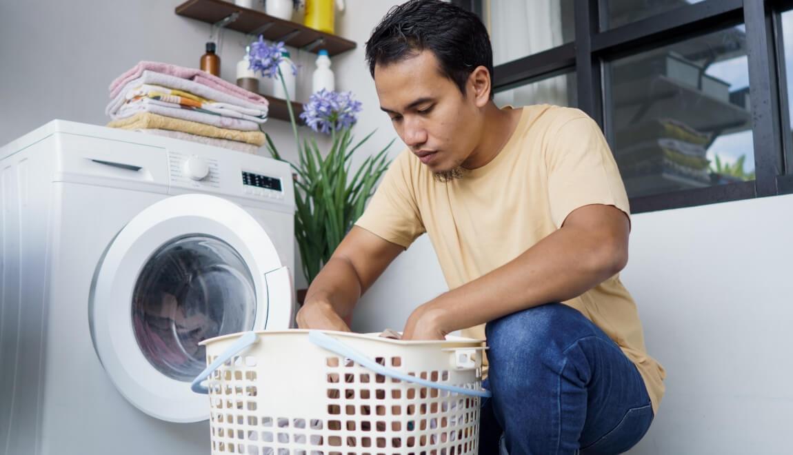 Renter loads his laundry in his washer and dryer.