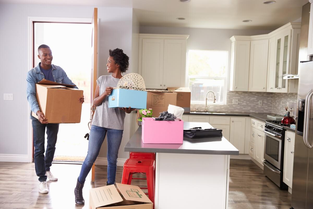 A young couple carry boxes into a new apartment.