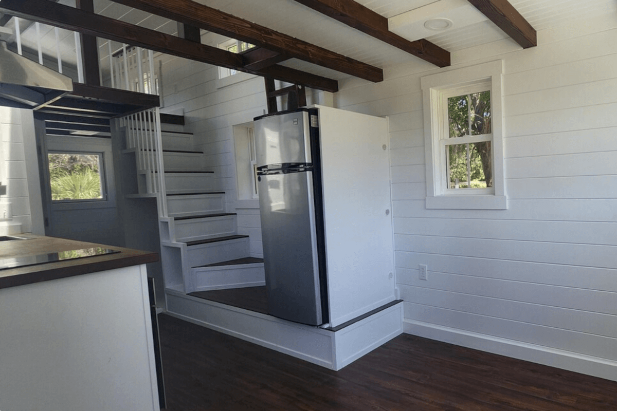 The inside of a tiny home in Florida shows a staircase tucked in the corner of the kitchen.