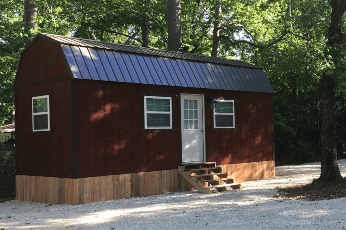 A red barndominium-style tiny home sits near a wooded area in Conroe, Texas.