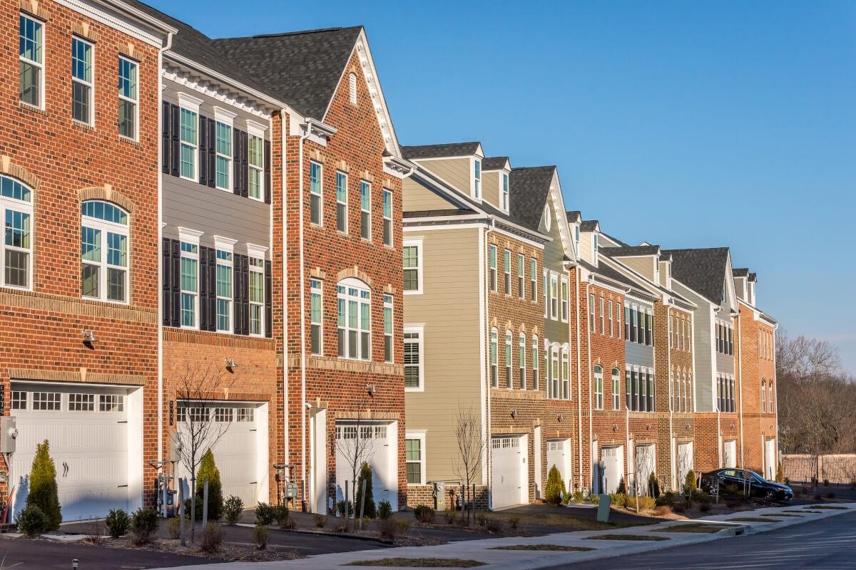 A row of brick townhomes each have a garage on the ground floor.