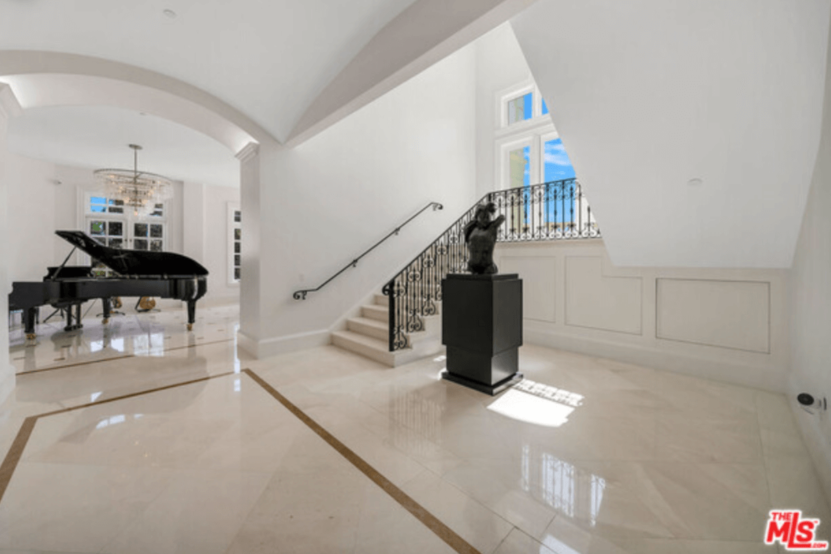 The foyer of 1141 Summit Drive features a sculpture in front of an ornate staircase.