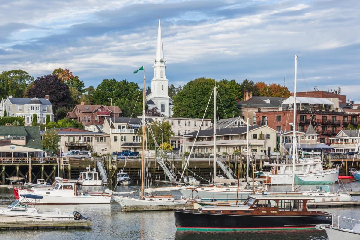 Ships moor in Camden Harbor with charming buildings in the background