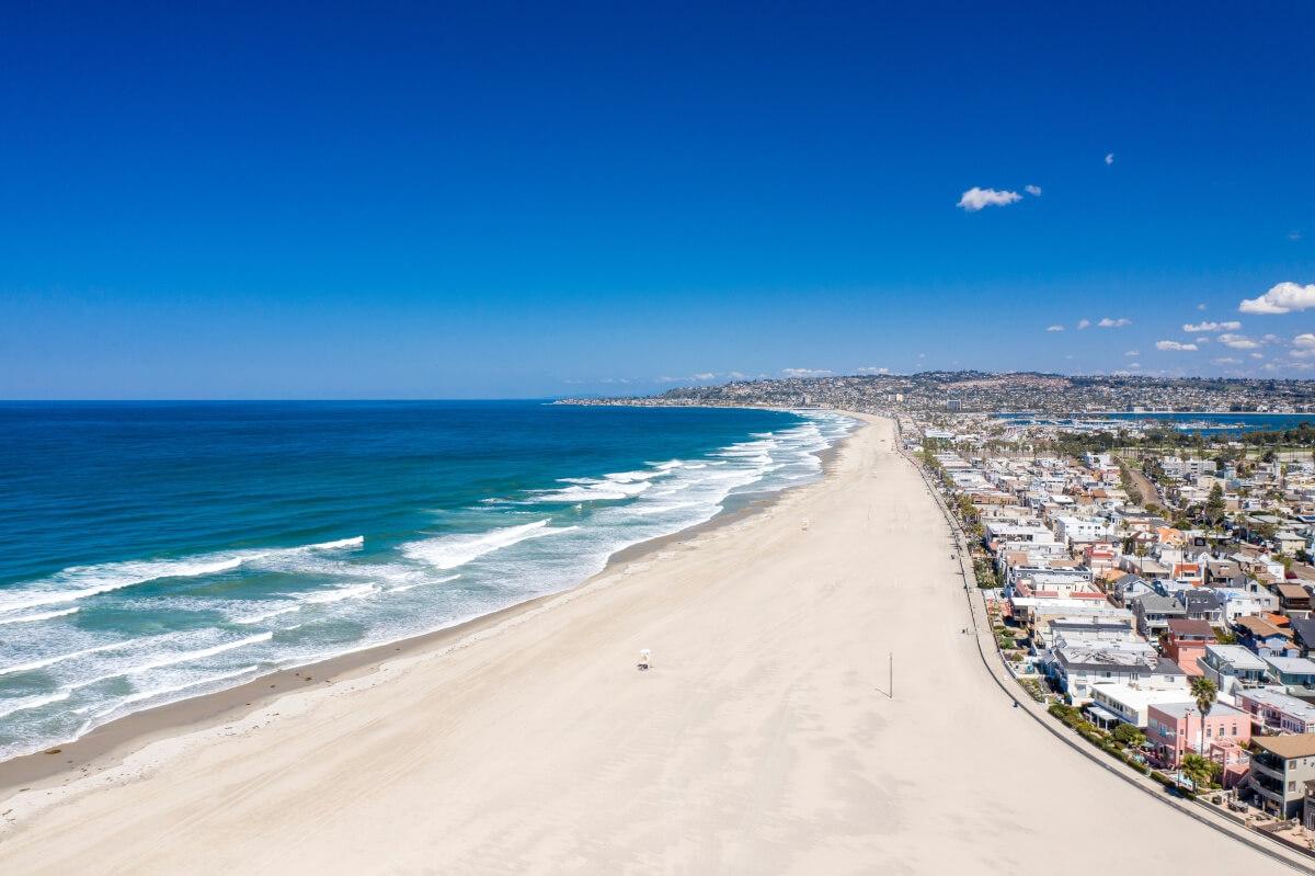 A coastal view of Ocean Beach with a variety of buildings on the right.