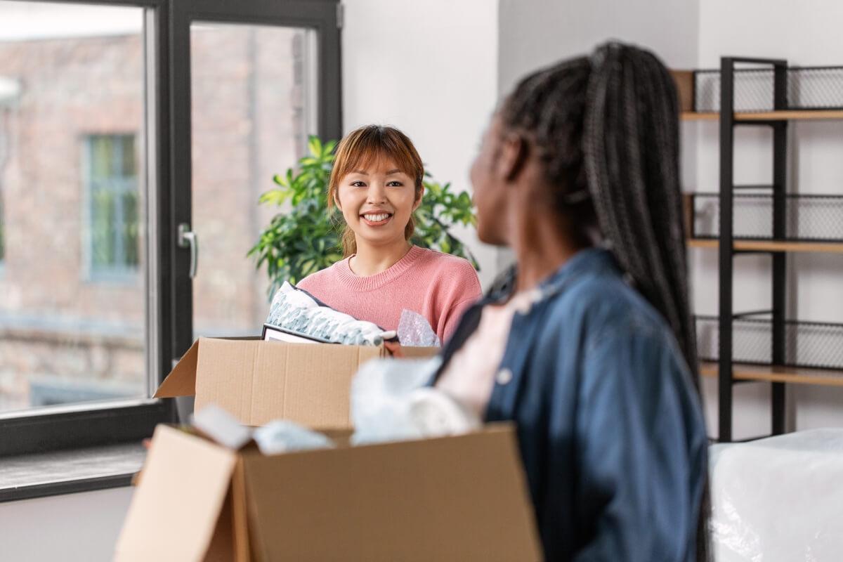 Roommates chat while moving into their new apartment. 