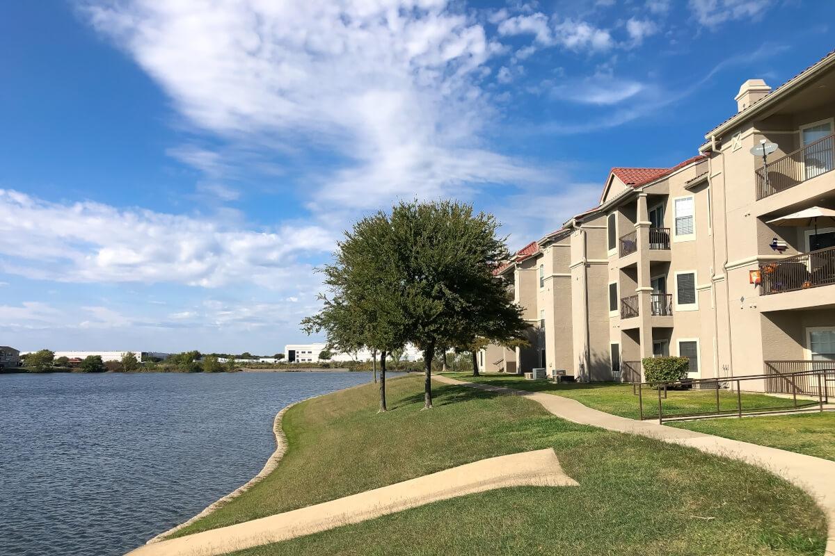 A stucco apartment complex overlooks a pond.