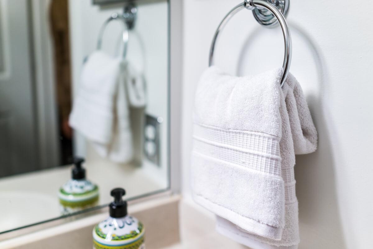 A close-up shot of a bathroom hand towel is reflected in a mirror above a sink.