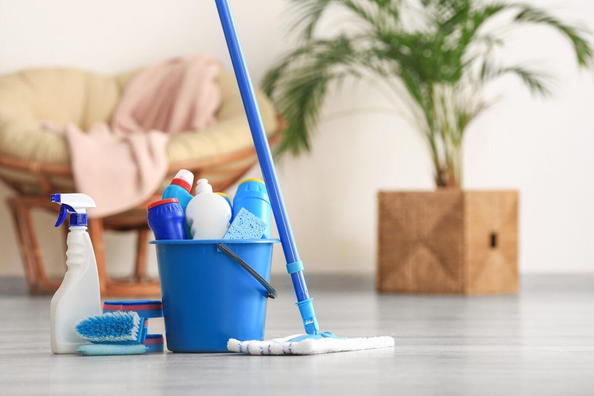 A bucket of cleaning supplies sits on the floor of an apartment.