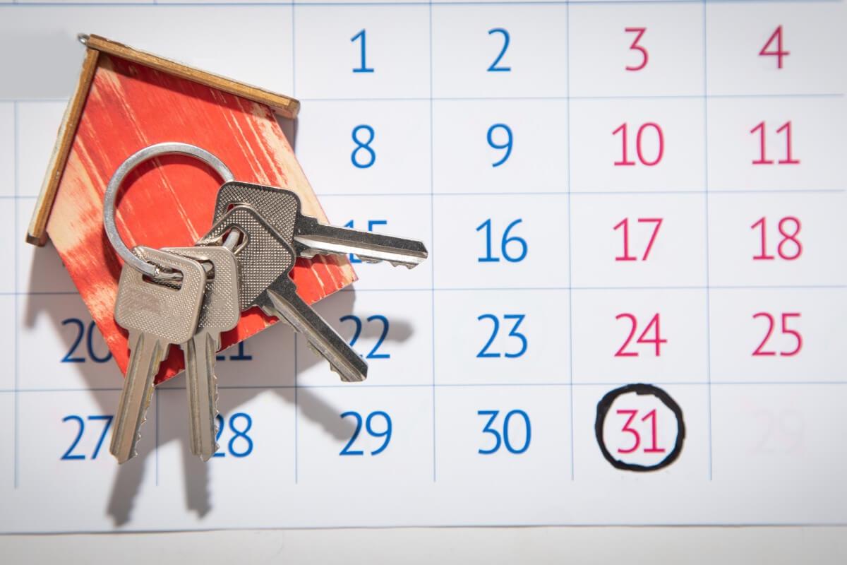 Calendar with a circle around a date with a wooden house with keys on top.