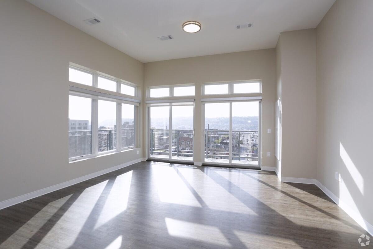 Sunlight streams into an apartment unit through large windows looking out to Downtown Pittsburgh.