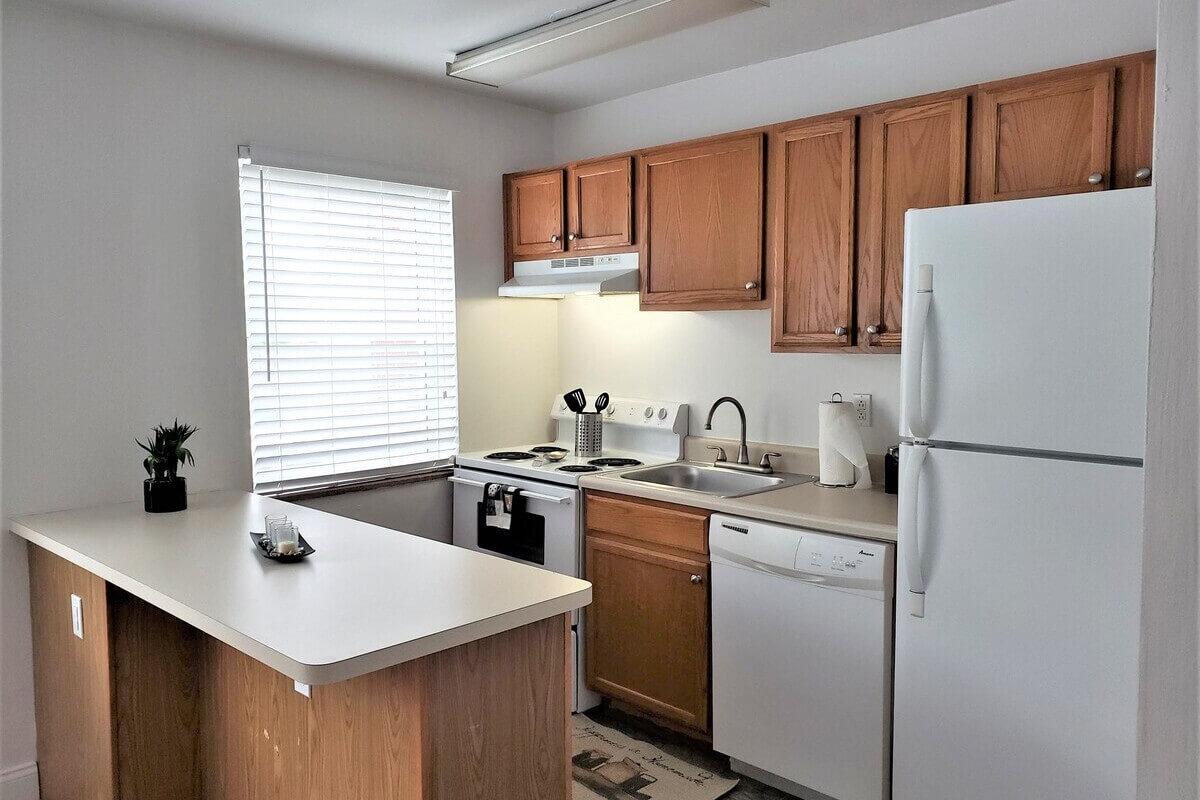 A cozy kitchen at Pacific Highlands Apartments in North Allegheny features a dishwasher, four-burner stove, and a breakfast counter.