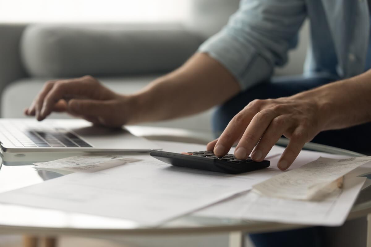 Person calculating rental application fees on calculator.
