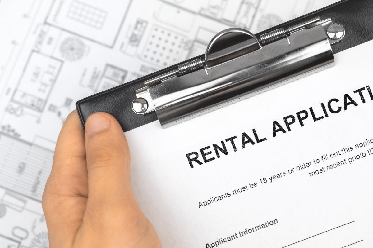 Person holding a clipboard with a rental application on it.