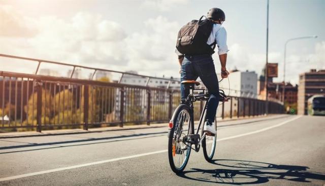 A man riding a bicycle down a paved road