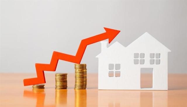 An arrow pointing up sitting on a stack of coins next to the cutout of a house.