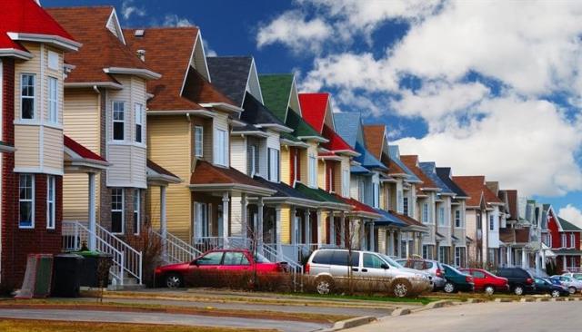 Tandemly parked cars in front of a row of townhomes.