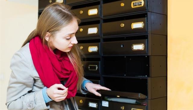 Woman glancing at an empty mailbox.