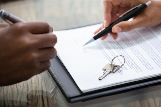 Two people review a lease with keys sitting on top of the agreement.