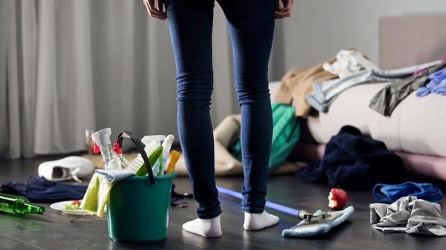 A person stands in the middle of a messy apartment.