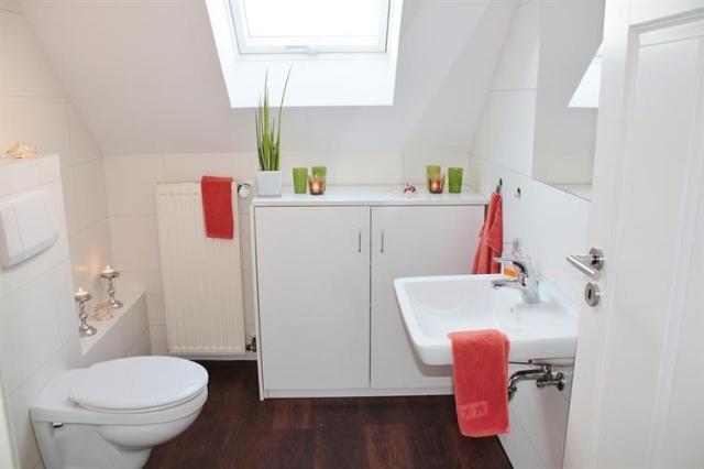 White bathroom with red accents and a skylight.