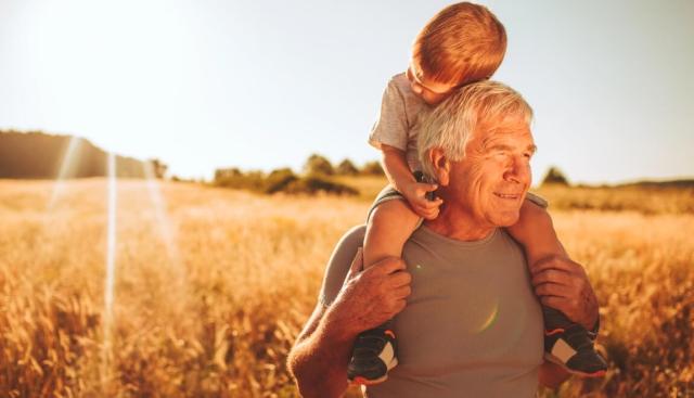 An older man with a young child on his shoulders.