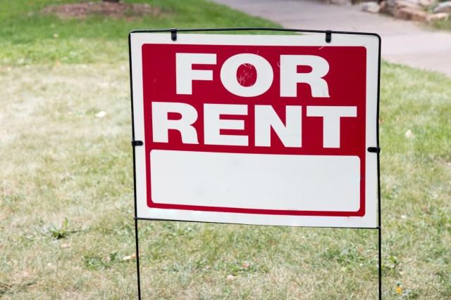 A "For Rent" sign stands in a front yard.