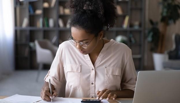 Person leaning over papers and a calculator.