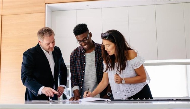 A couple reviews a lease with a property manager in an apartment.