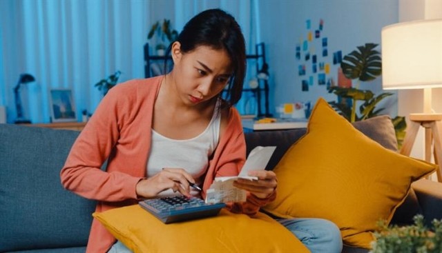 Woman using a calculator to add up receipts. 