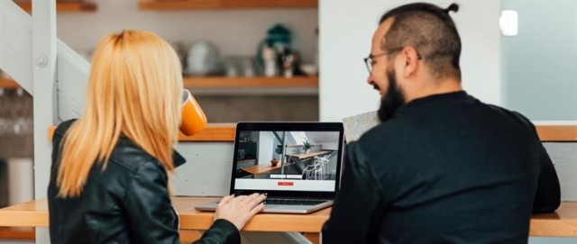 Two individuals gather around a laptop to search for an apartment