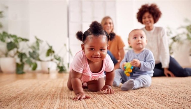 Two babies play together in an apartment.