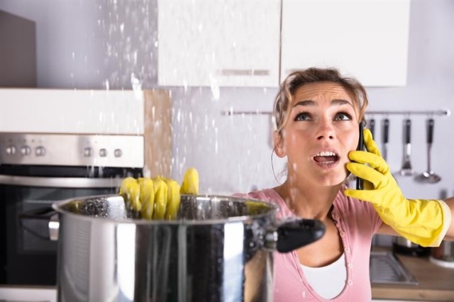 A woman catching water flowing from the ceiling