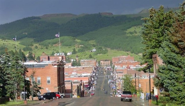 A small town on rolling hills with mountains in the distance.