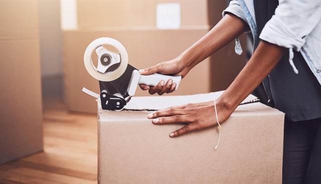 Hands packing up a moving box