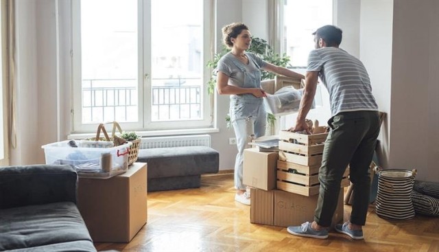 Couple lifting boxes during apartment move-out.