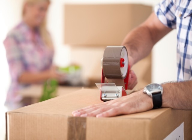 A hand taping a box shut with packing tape