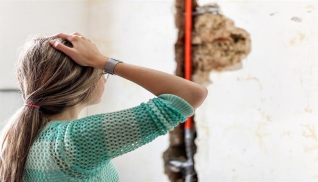 Woman ponders over a pipe in the wall