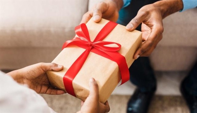 Two people handing over a holiday gift wrapped with a red bow