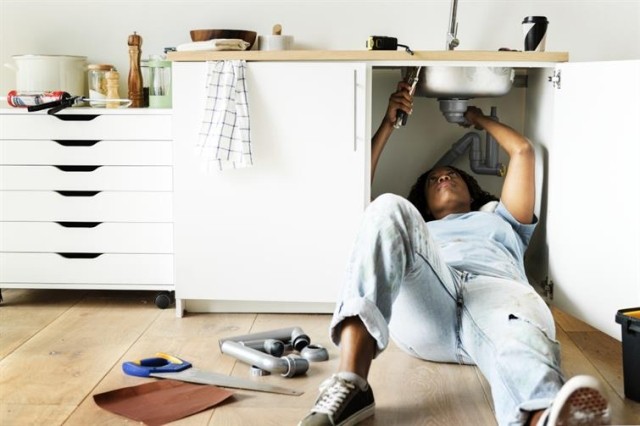 A person trying to repair a kitchen sink.