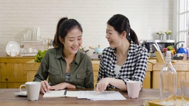 Two roommates sitting in the kitchen reviewing their budget.